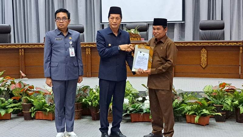 Pj Bupati Barito Utara Drs Muhlis didampingi Asisten Sekda Eveready Noor menyerahkan materi raperda untuk dibahas bersama dalam rapat gabungan komisi