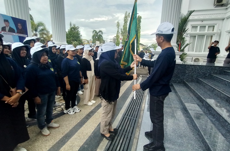 LAMBANG DAERAH-Pj Bupati Barito Utara Drs Muhlis menyerahkan bendera lambang daerah kepada Kepala Dinas Kebudayaan Pariwisata Kepemudaan dan Olahraga Barito Utara Hj Annisa Cahyawati usai pelepasan kontingen FBIM di halaman rumah jabatan bupati, Minggu (12/5/2024).